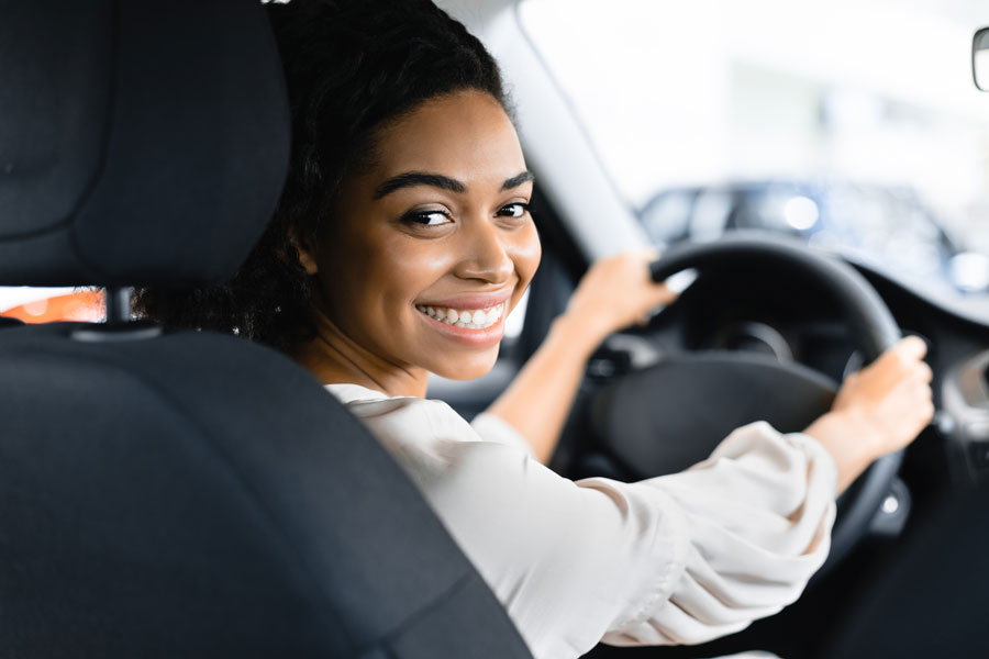 Photo femme souriant au volant du véhicule en location longue durée